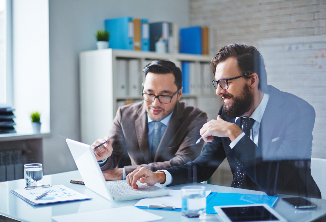 Two business professionals in suits reviewing financial data on a laptop in an office, representing CFOs discussing strategic priorities and FP&A tools.
